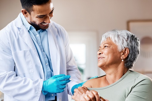 Shot of a doctor giving an older woman an injection at home