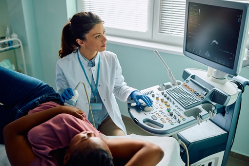 Gynecologist using ultrasound during medical examination of black woman at clinic.