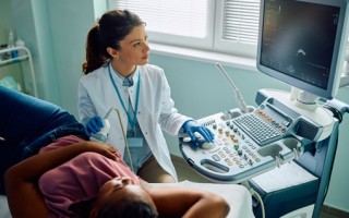 Gynecologist using ultrasound during medical examination of black woman at clinic.